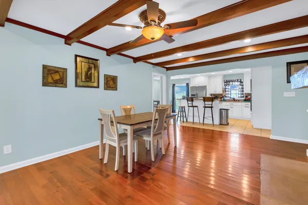 a dining room with wooden floor a chandelier a glass table and chairs