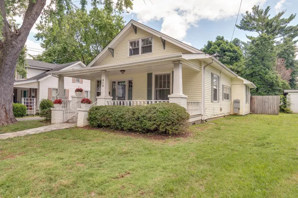 a view of a white house with a big yard and large trees