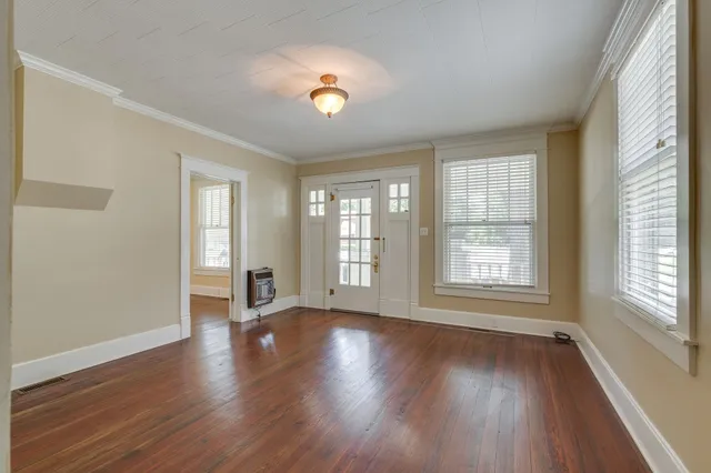 an empty room with wooden floor and windows