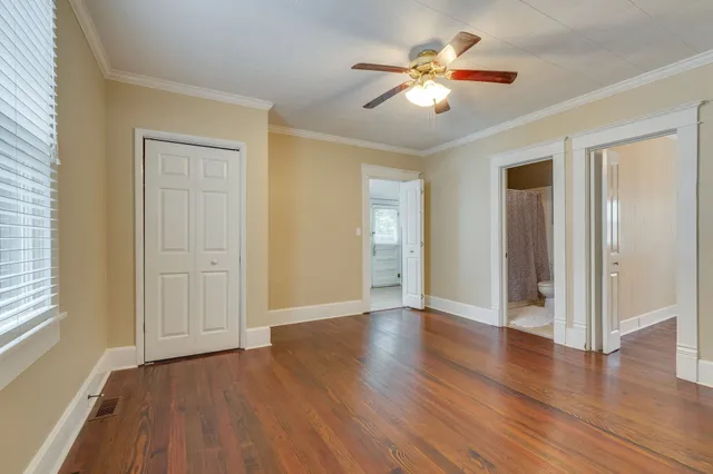 an empty room with wooden floor and ceiling fan