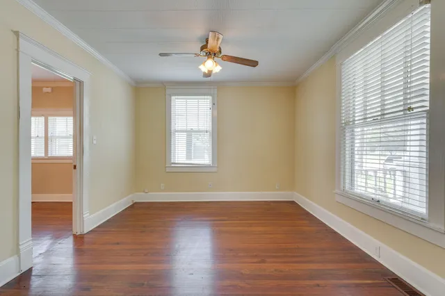 an empty room with wooden floor and windows