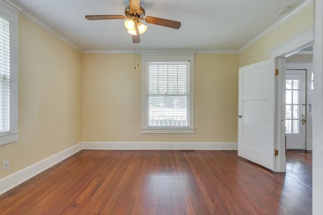 a view of an empty room with wooden floor and a window