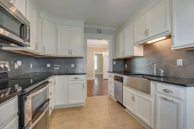 a kitchen with granite countertop white cabinets stainless steel appliances and a sink