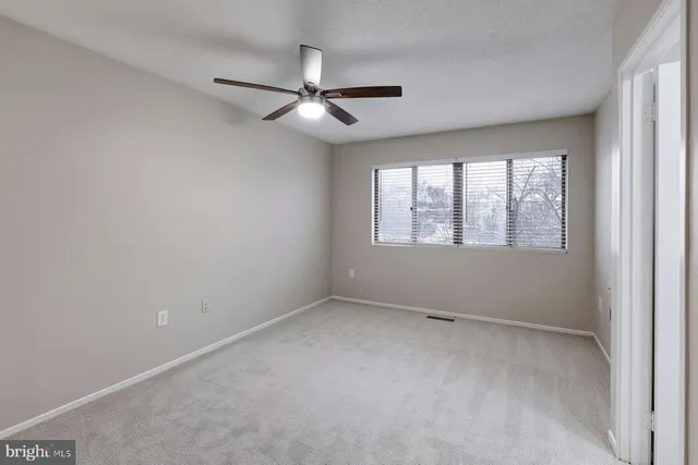 an empty room with a window and a fan