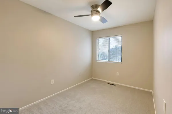 an empty room with a window and a ceiling fan