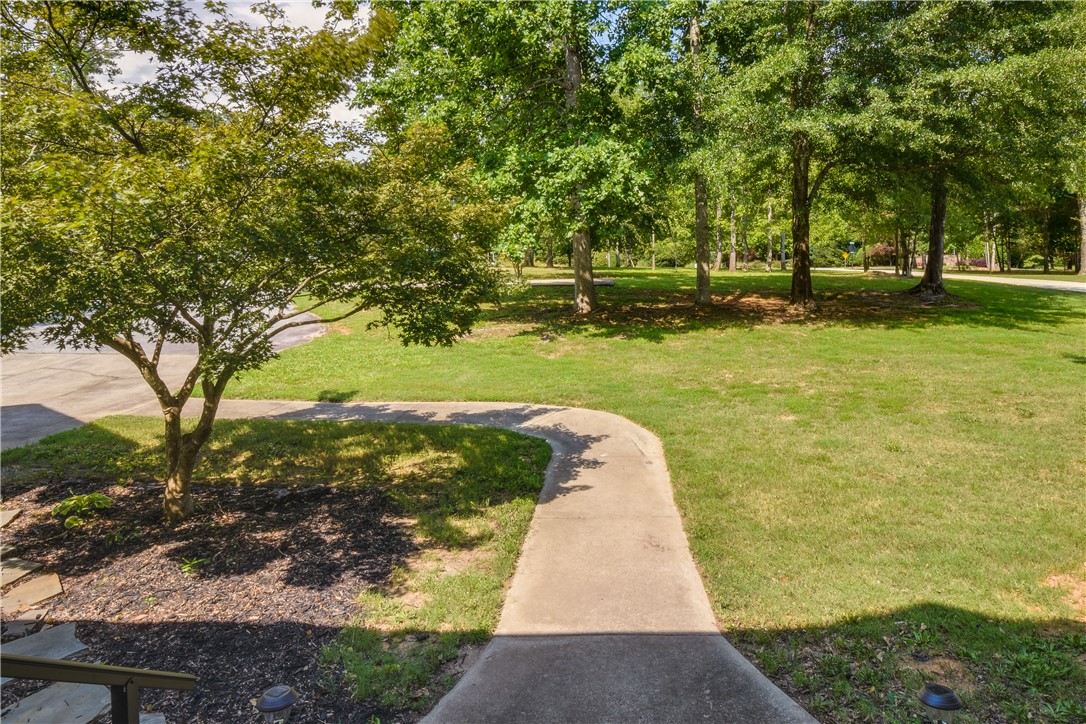 206 Petty Road Seneca, SC 29672 - Photo 46 of 48 A winding concrete path guides the way through a verdant lawn, framed by mature trees and lush landscaping.