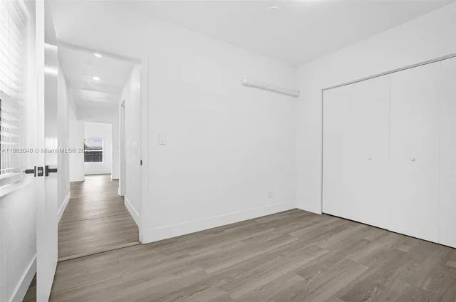 a view of a hallway with wooden floor and a door