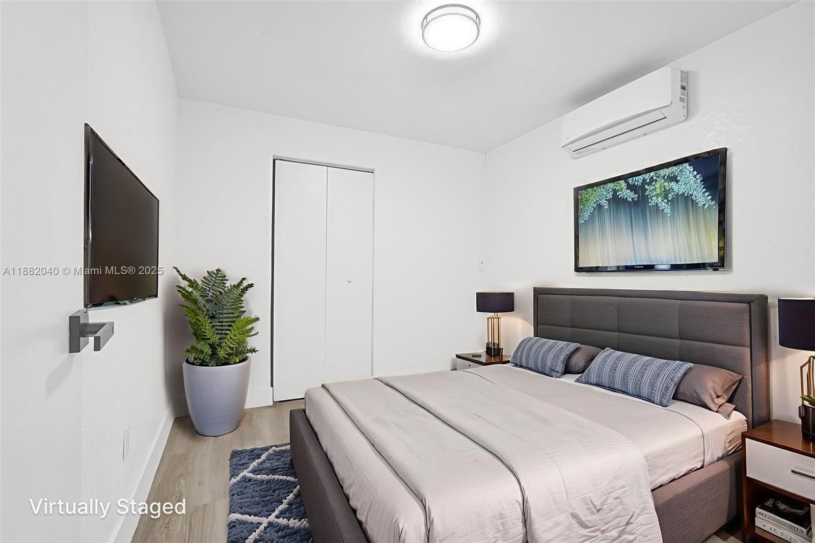 1090 Northwest 77th Street Miami, FL 33150 - Photo 52 of 77 a bedroom with a bed a potted plant and a flat screen tv