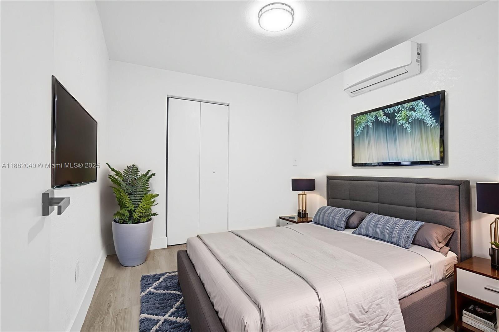 1090 Northwest 77th Street Miami, FL 33150 - Photo 53 of 77 a bedroom with a bed a potted plant and a flat screen tv