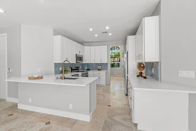 a kitchen with white cabinets stainless steel appliances and window