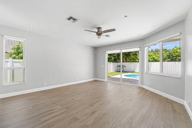 an empty room with wooden floor and windows