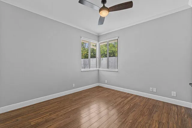 a view of an empty room with window and wooden floor