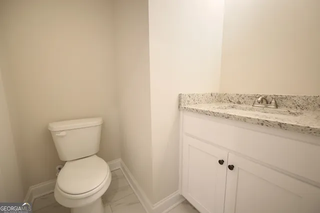 a bathroom with a granite countertop toilet and a sink