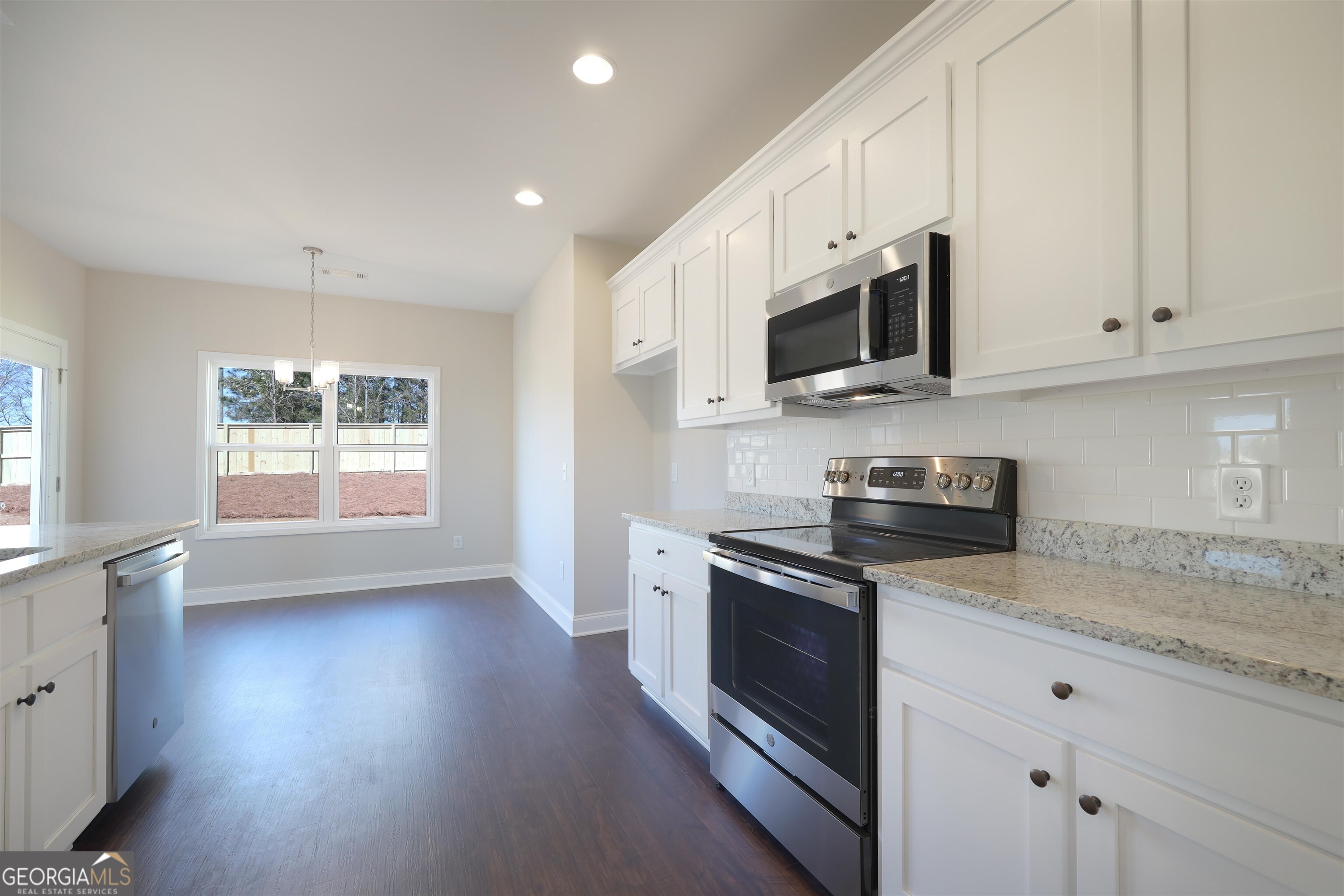 63 Delightful Way, Unit 1 Winder, GA 30680 - Photo 9 of 26 a kitchen with stainless steel appliances granite countertop a stove a sink and a microwave