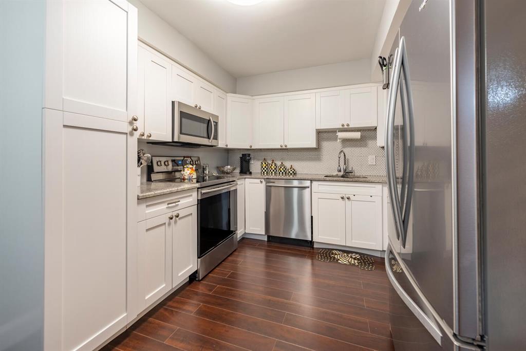 16251 Golf Club Road, Unit 305 Weston, FL 33326 - Photo 18 of 43 a kitchen with stainless steel appliances a sink cabinets and a wooden floor