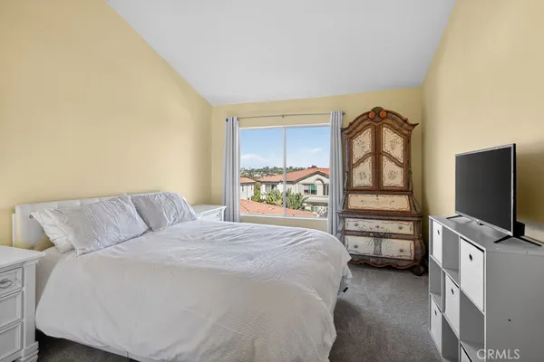 a bedroom with a bed and a flat tv screen on dresser