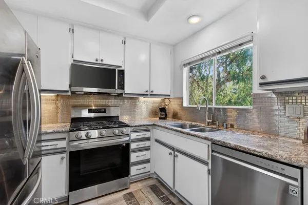 a kitchen with stainless steel appliances a stove sink microwave and refrigerator