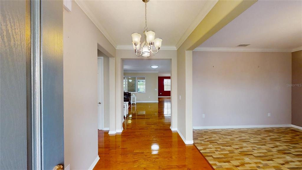 9273 Southwest 91st Ct Road Ocala, FL 34481 - Photo 4 of 38 a view of a hallway with wooden floor and a chandelier