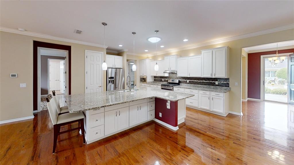 9273 Southwest 91st Ct Road Ocala, FL 34481 - Photo 10 of 38 a large kitchen with stainless steel appliances kitchen island granite countertop a stove a sink a refrigerator and white cabinets with wooden floor