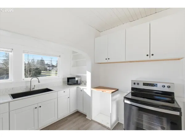 a kitchen with appliances a sink a window and cabinets