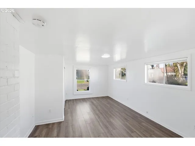 a view of an empty room with window and wooden floor