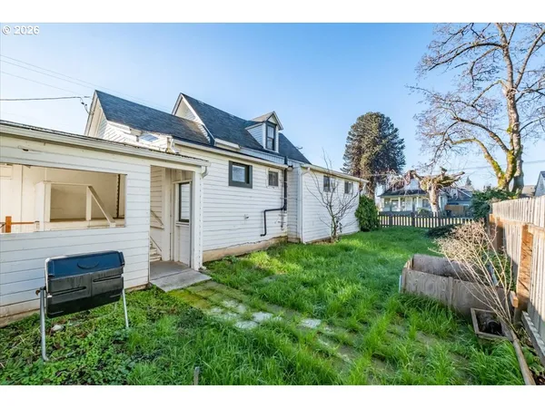 a view of backyard of house with wooden fence