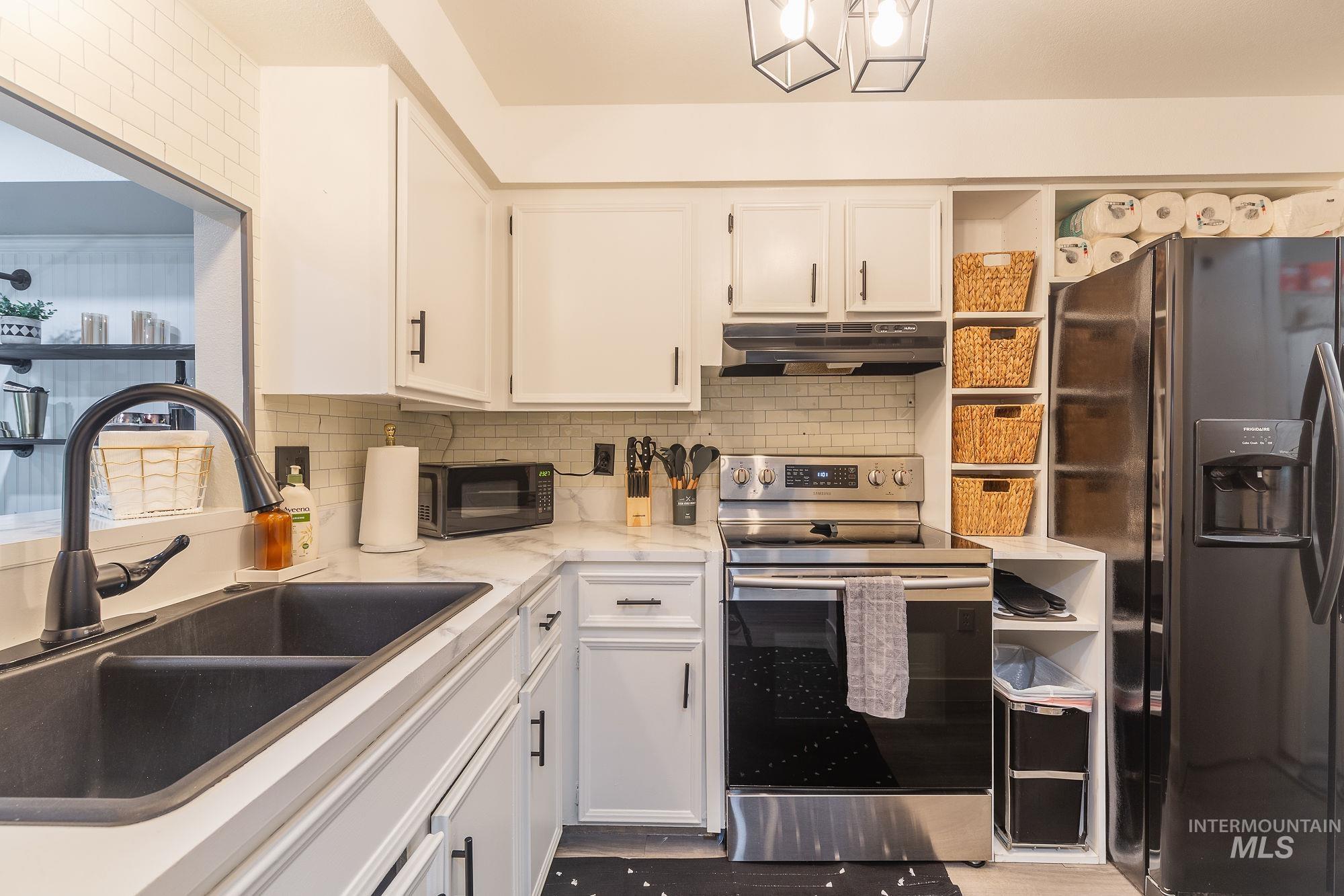 352 North Eagle Road Eagle, ID 83616 - Photo 16 of 44 Kitchen with refrigerator with ice dispenser, under cabinet range hood, stainless steel electric range, black microwave, and white cabinets