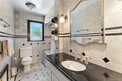 a bathroom with a granite countertop sink toilet and mirror