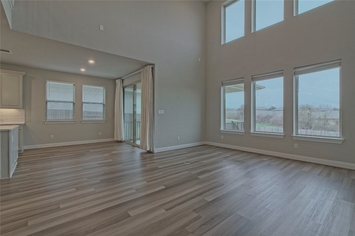 324 Windom Way Georgetown, TX 78626 - Photo 12 of 40 Unfurnished living room featuring healthy amount of natural light, light wood-type flooring, and a towering ceiling