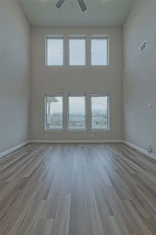 a view of an empty room with wooden floor and window