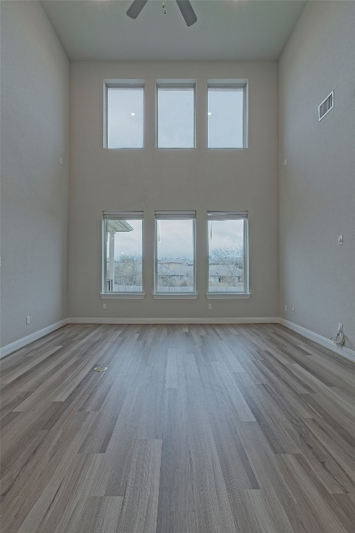 324 Windom Way Georgetown, TX 78626 - Photo 13 of 40 Unfurnished living room with a towering ceiling, light wood-type flooring, healthy amount of natural light, and ceiling fan