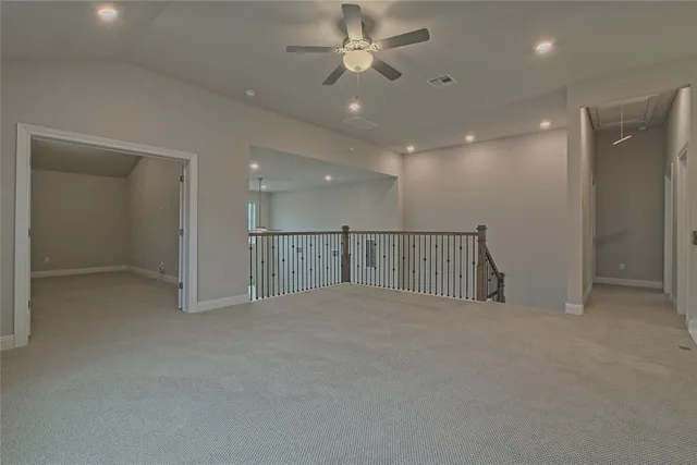 an empty room with chandelier fan and windows