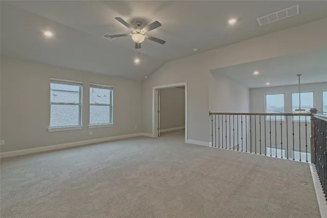 an empty room with chandelier fan and windows