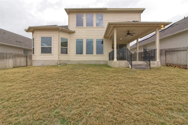 an empty room with a chandelier fan and windows