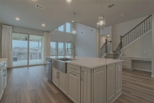 a large kitchen with a center island wooden floor and stainless steel appliances