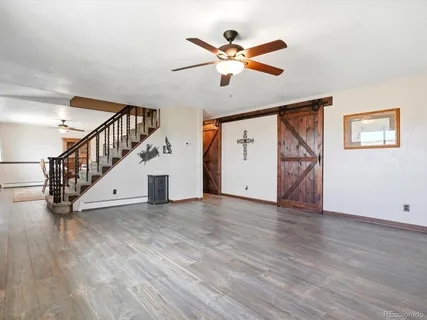 a view of an empty room with wooden floor and a ceiling fan