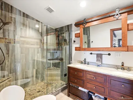a bathroom with a granite countertop sink toilet mirror and shower