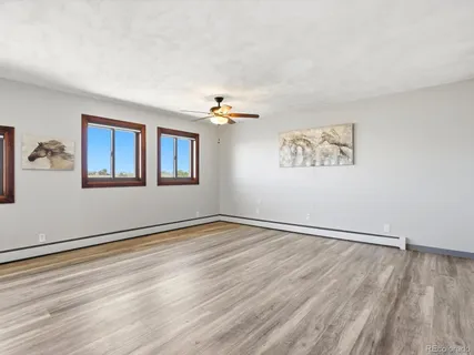 a view of a room with wooden floor and a ceiling fan