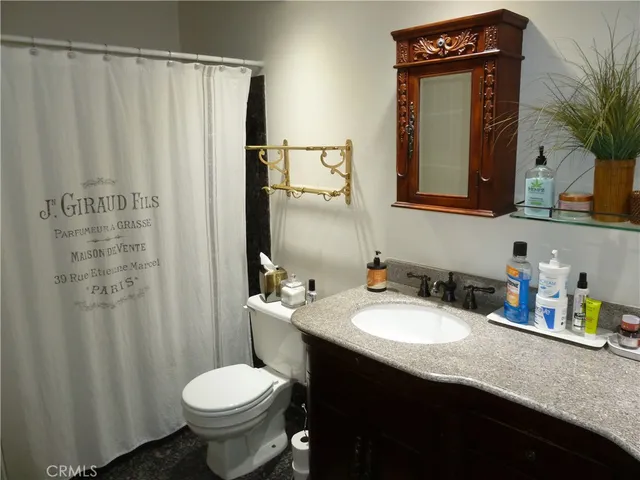 a bathroom with a granite countertop sink toilet and mirror