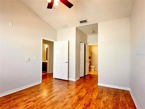an empty room with closet and a chandelier fan