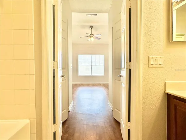 a view of a hallway with wooden floor and a bathroom