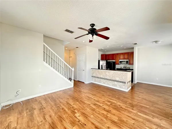 a view of a living room and a kitchen with wooden floor