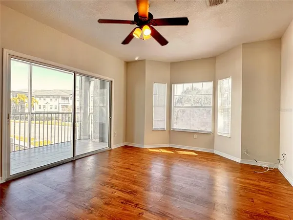 a view of an empty room with window and wooden floor