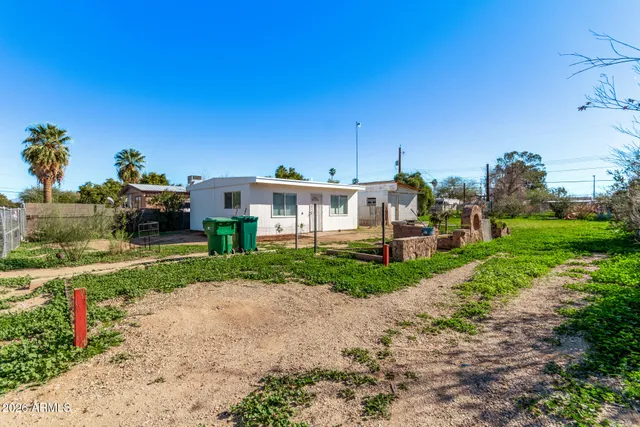 a view of a house with a yard and table and chairs under an umbrella