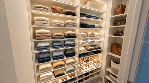 a view of walk in closet with clothes and shoes