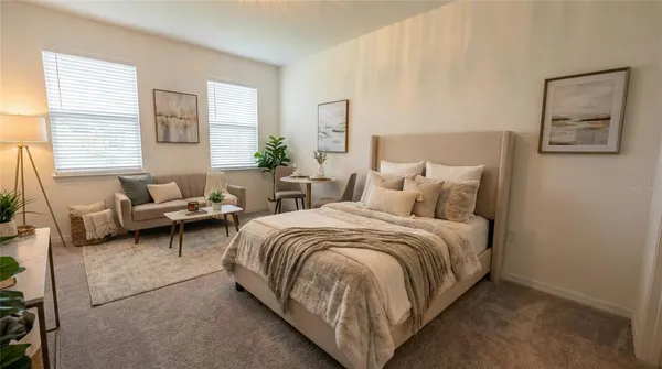 a spacious bedroom with a bed a couch and windows