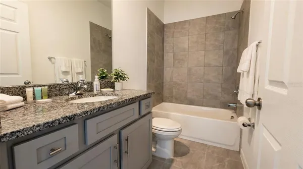 a bathroom with a granite countertop sink a toilet and bathtub