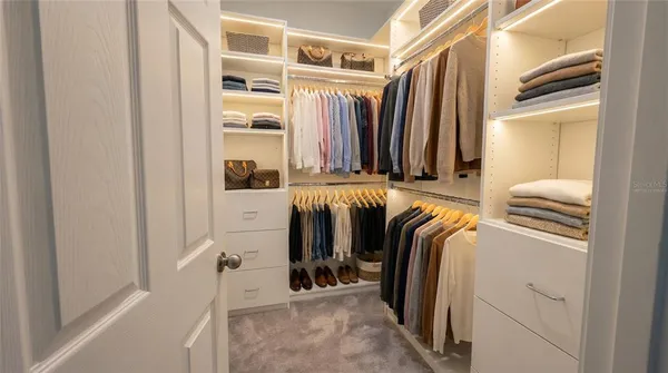 a view of walk in closet with clothes and shoes