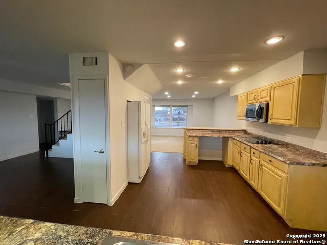 a large kitchen with stainless steel appliances kitchen island granite countertop a large counter top and a stove top oven