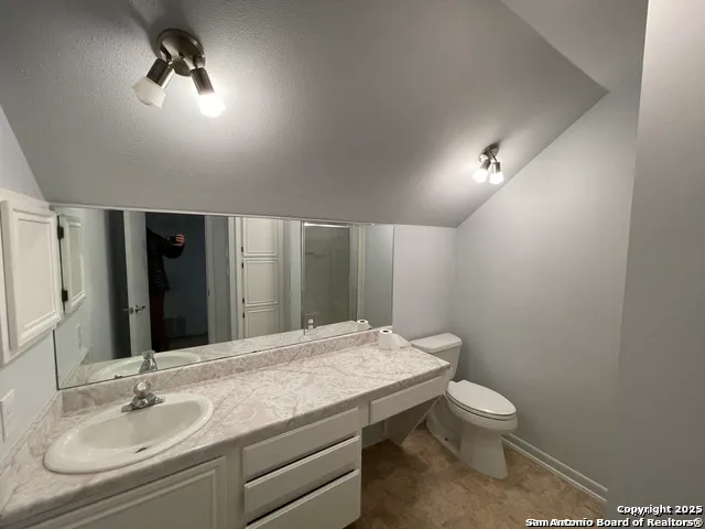 a bathroom with a granite countertop sink a toilet and mirror